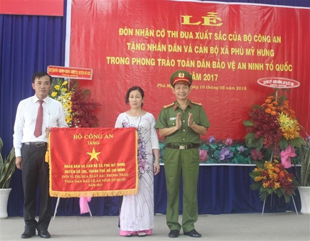 Đại tá Đinh Thanh Nhàn, Phó Giám đốc Công an TP. Hồ Chí Minh trao Cờ thi đua xuất sắc trong phong trào Toàn dân bảo vệ an ninh Tổ quốc năm 2017 tặng nhân dân và cán bộ xã Phú Mỹ Hưng.