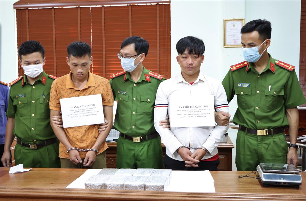 Hai đối tượng Ly Chờ Tùng (áo trắng) và Giàng A Cu (áo vàng) cùng 16 bánh heroin tại cơ quan điều tra.