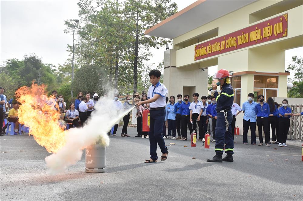 Lực lượng Cảnh sát PCCC và CNCH hướng dẫn các em học sinh sử dụng bình chữa cháy xách tay để dập lửa.