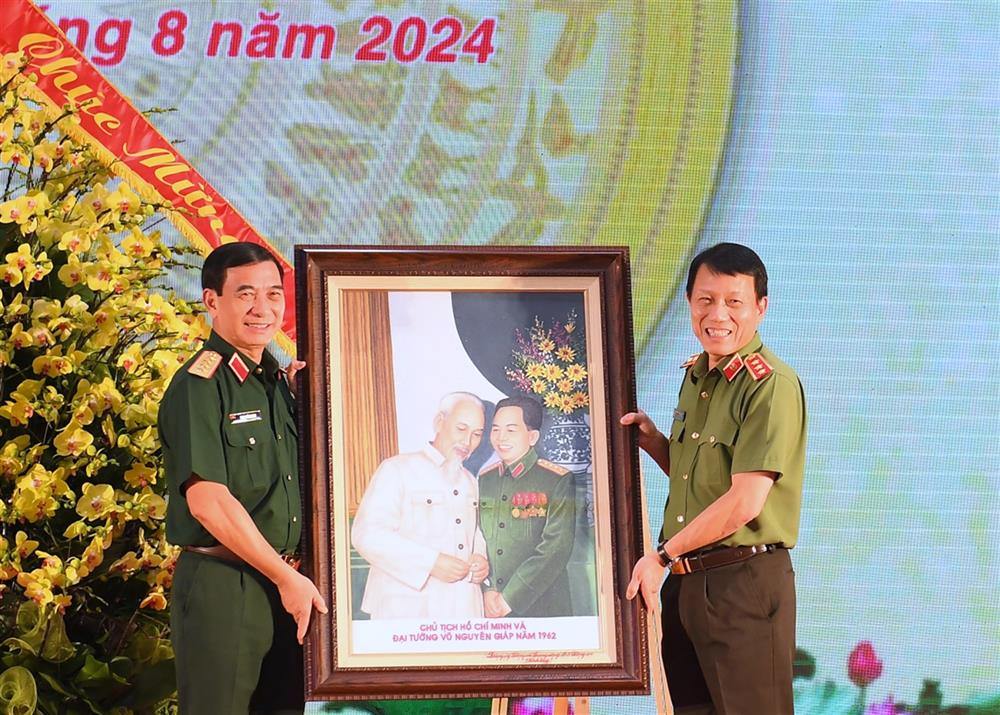 Thay mặt Đảng ủy Công an Trung ương, Bộ Công an, Bộ trưởng Lương Tam Quang trao bức ảnh lưu niệm tặng Quân ủy Trung ương, Bộ Quốc phòng.