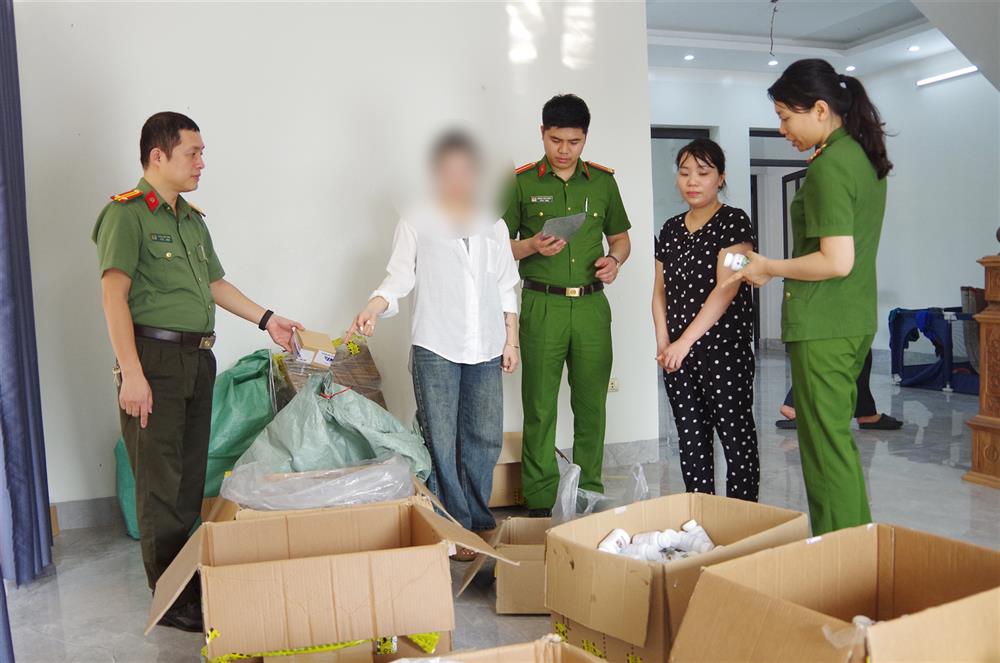 Hồ Thị Hoa (áo đen) và hàng giả là thuốc chữa bệnh bị thu giữ.