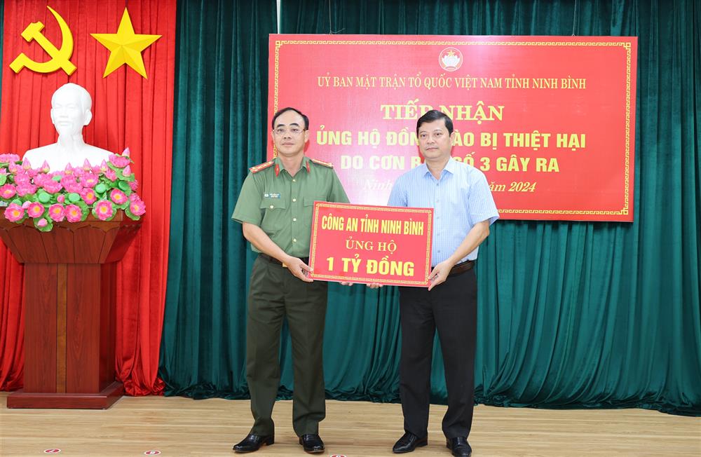 Đại tá Trần Hồng Phú, Phó Giám đốc Công an tỉnh trao tiền ủng hộ đồng bào bị thiệt hại do cơn bão số 3 cho Mặt trận Tổ quốc Việt Nam tỉnh Ninh Bình.