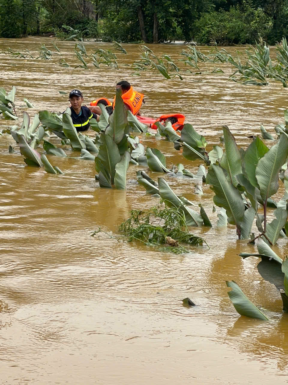Chiến sĩ Công an khoác áo phao, lội bùn sâu, đưa từng người dân ra khỏi khu vực nguy hiểm.