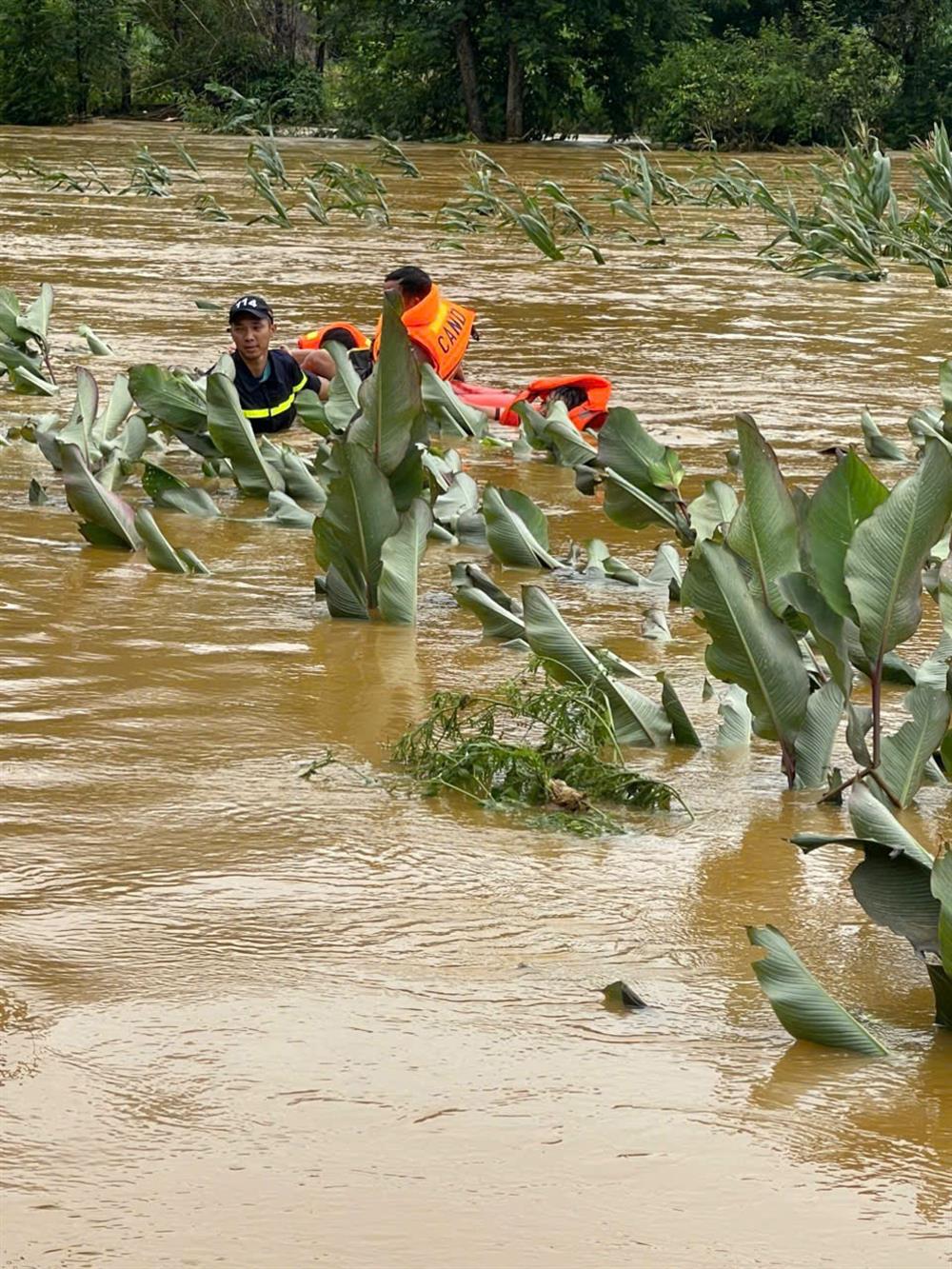 Chiến sĩ Công an khoác áo phao, lội bùn sâu, đưa từng người dân ra khỏi khu vực nguy hiểm.