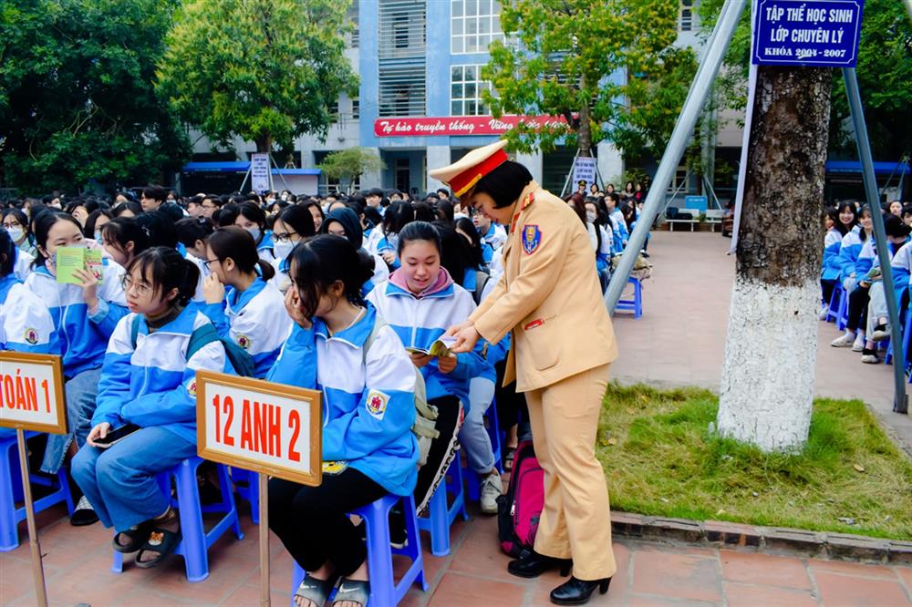 Cán bộ phòng Cảnh sát giao thông phát tài liệu tuyên truyền cho các em học sinh.
