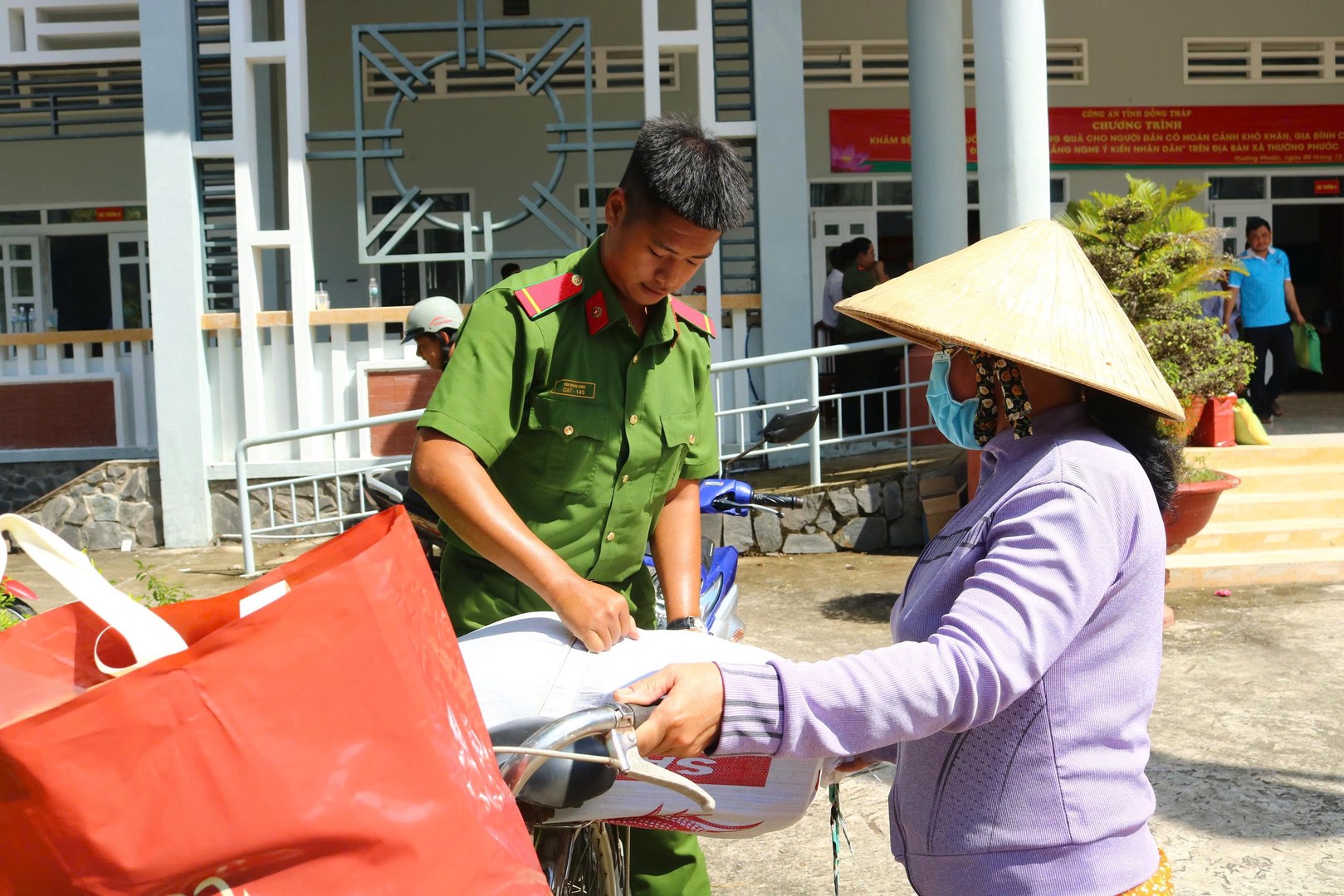 Lực lượng đoàn viên Công an tỉnh hỗ trợ người dân đem quà về sau khi khám bệnh và phát thuốc miễn phí. Ảnh Phước Thanh.jpg