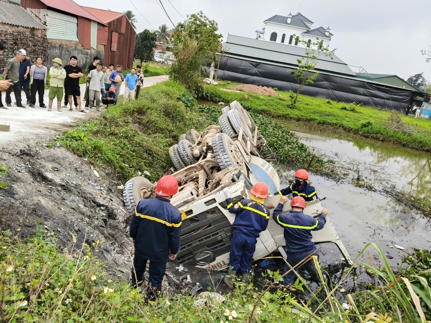 Lực lượng PCCC và CNCH Công an tỉnh Bắc Ninh đang tiếp cận chiếc xe trộn bê tông bị đổ lật để giải cứu nạn nhân đang mắc kẹt trong xe.jpg