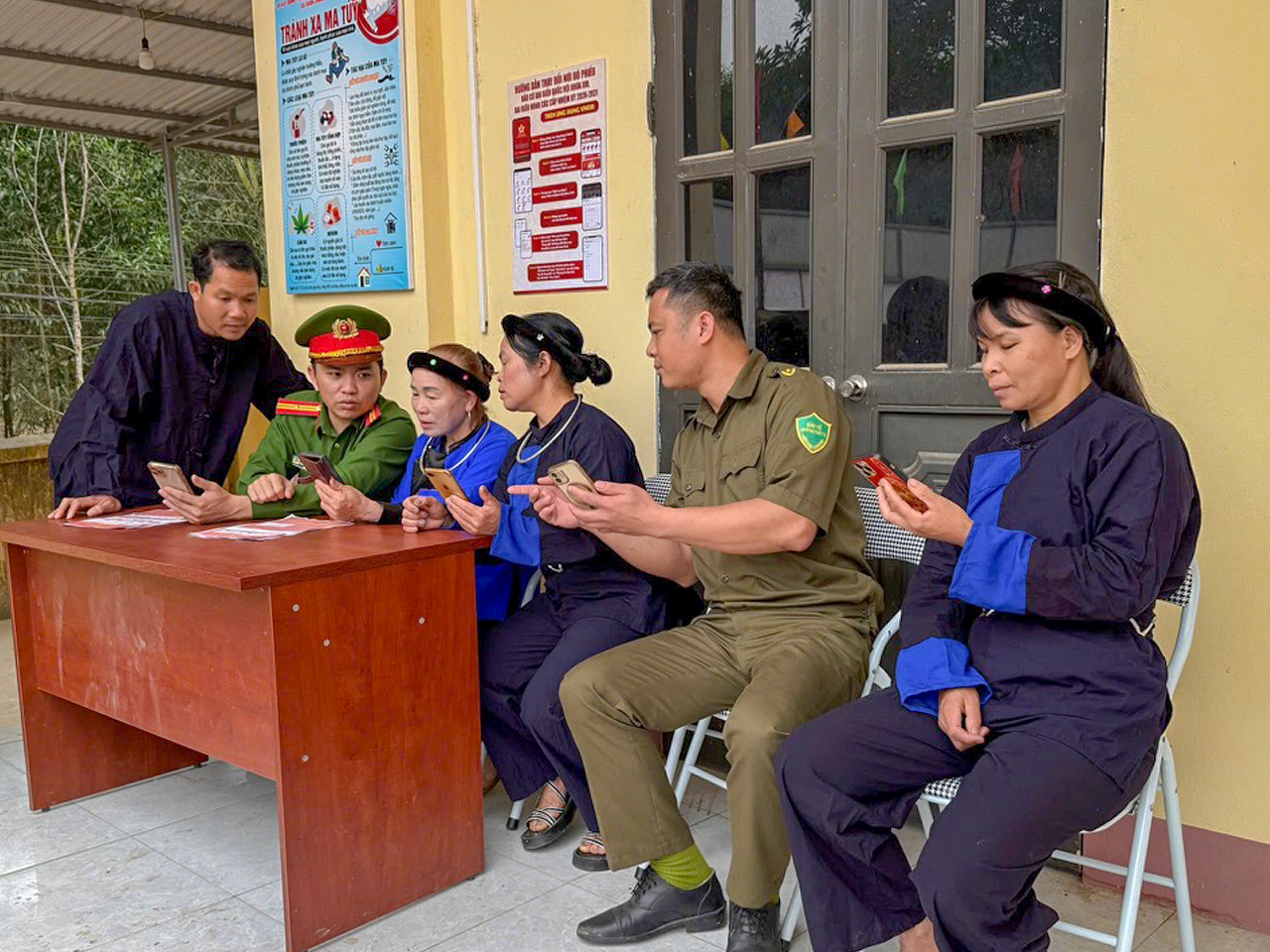 Cán bộ Công an xã và thành viên Tổ bảo vệ ANTT bản Trại Sông, xã Xuân Lương hướng dẫn người dân đăng ký tài khoản an sinh xã hội trên ứng dụng VNeID.jpg