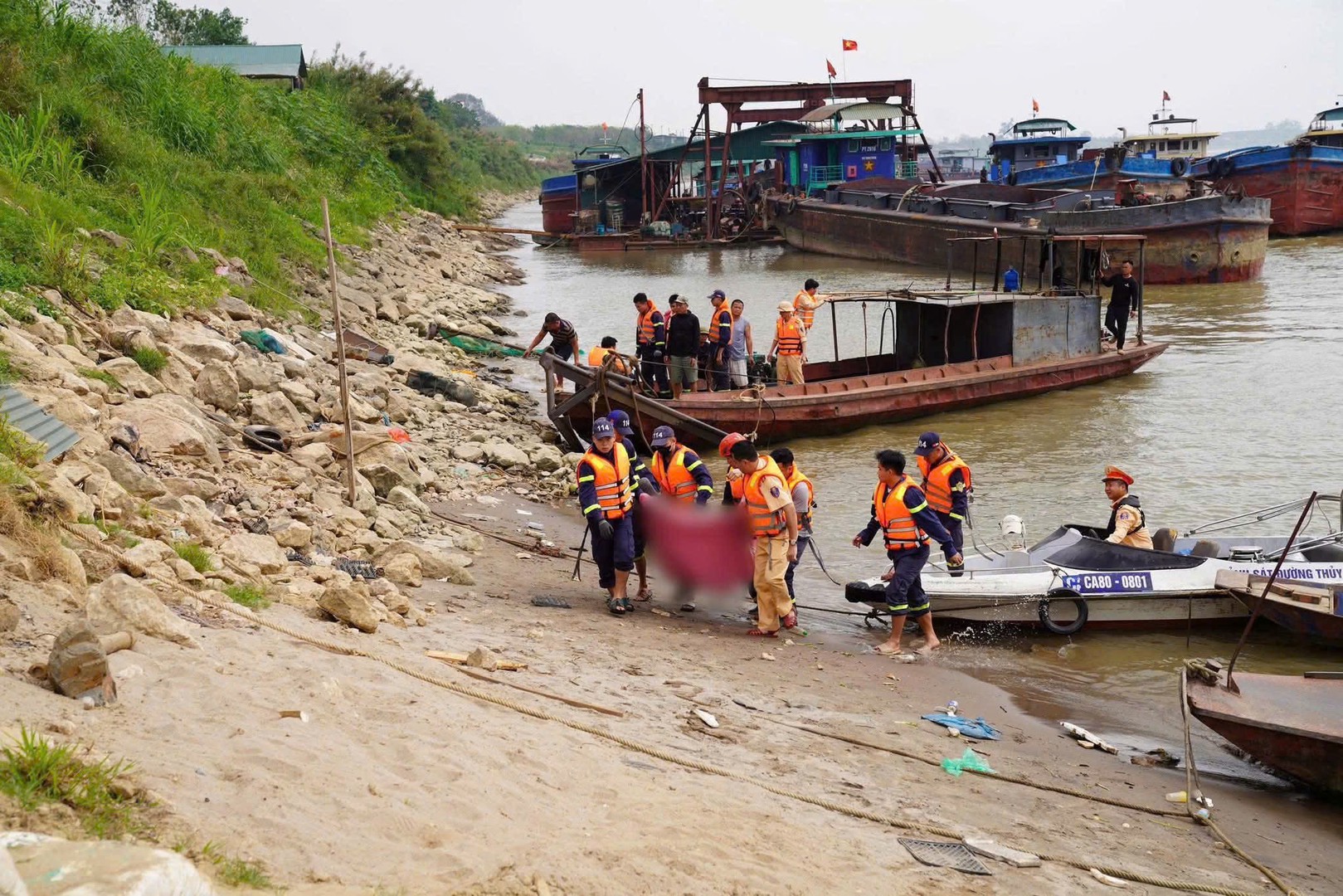 Lực lượng cứu hộ đưa thi thể một nạn nhân lên bờ.jpg