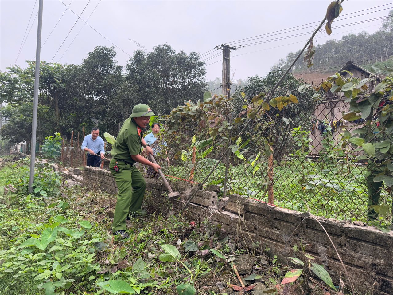 Cán bộ chiến sỹ Công an xã Tân Hợp cùng người dân thóa dỡ tường bao, đo đạc giải phóng mặt bằng phục vụ mở rộng tuyến đường.jpg