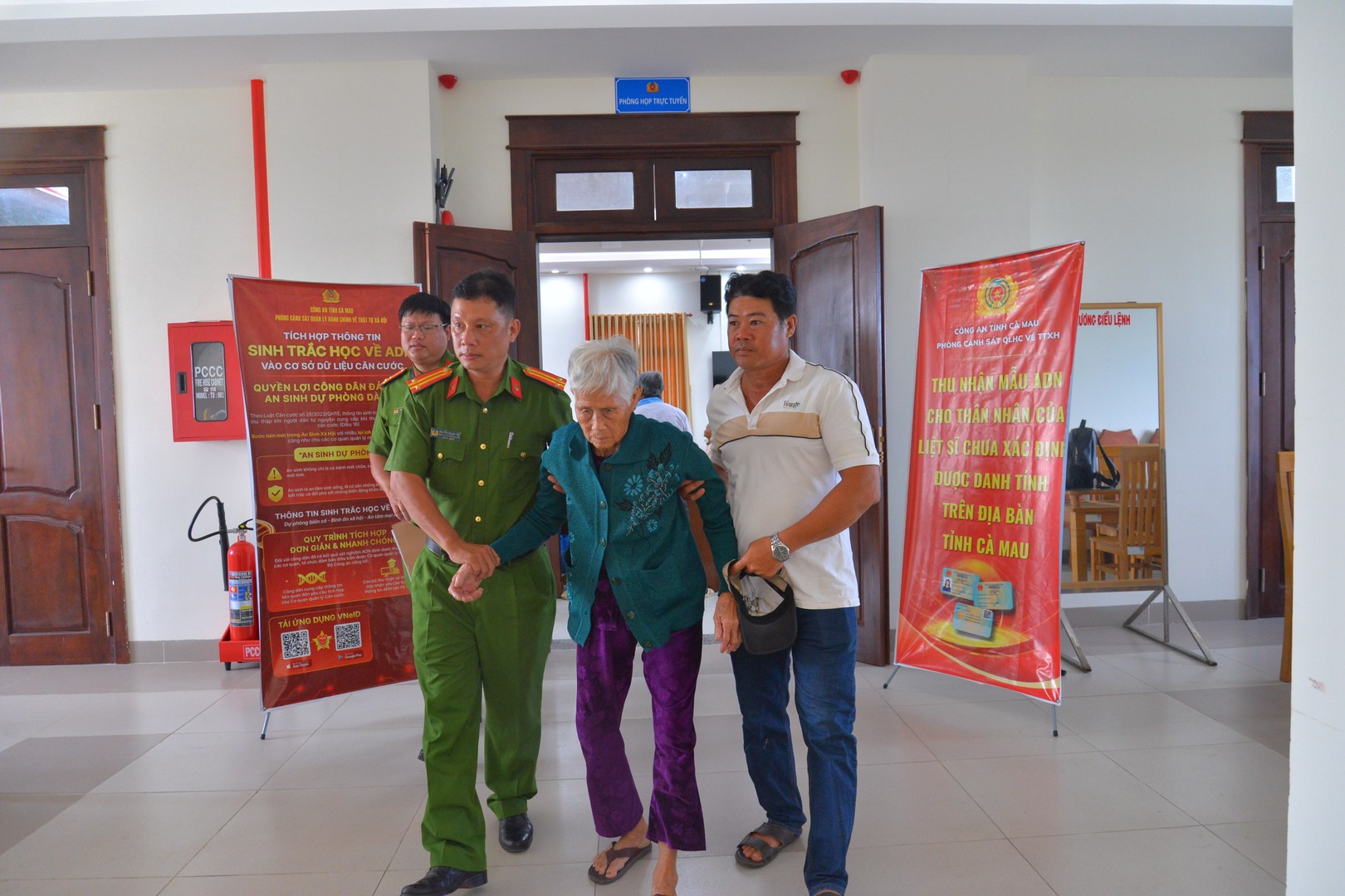 Ảnh 1- Cán bộ Công an cấp xã ân cần hỗ trợ đưa, rước thân nhân Liệt sĩ già yếu đến điểm thu nhận mẫu AD.JPG