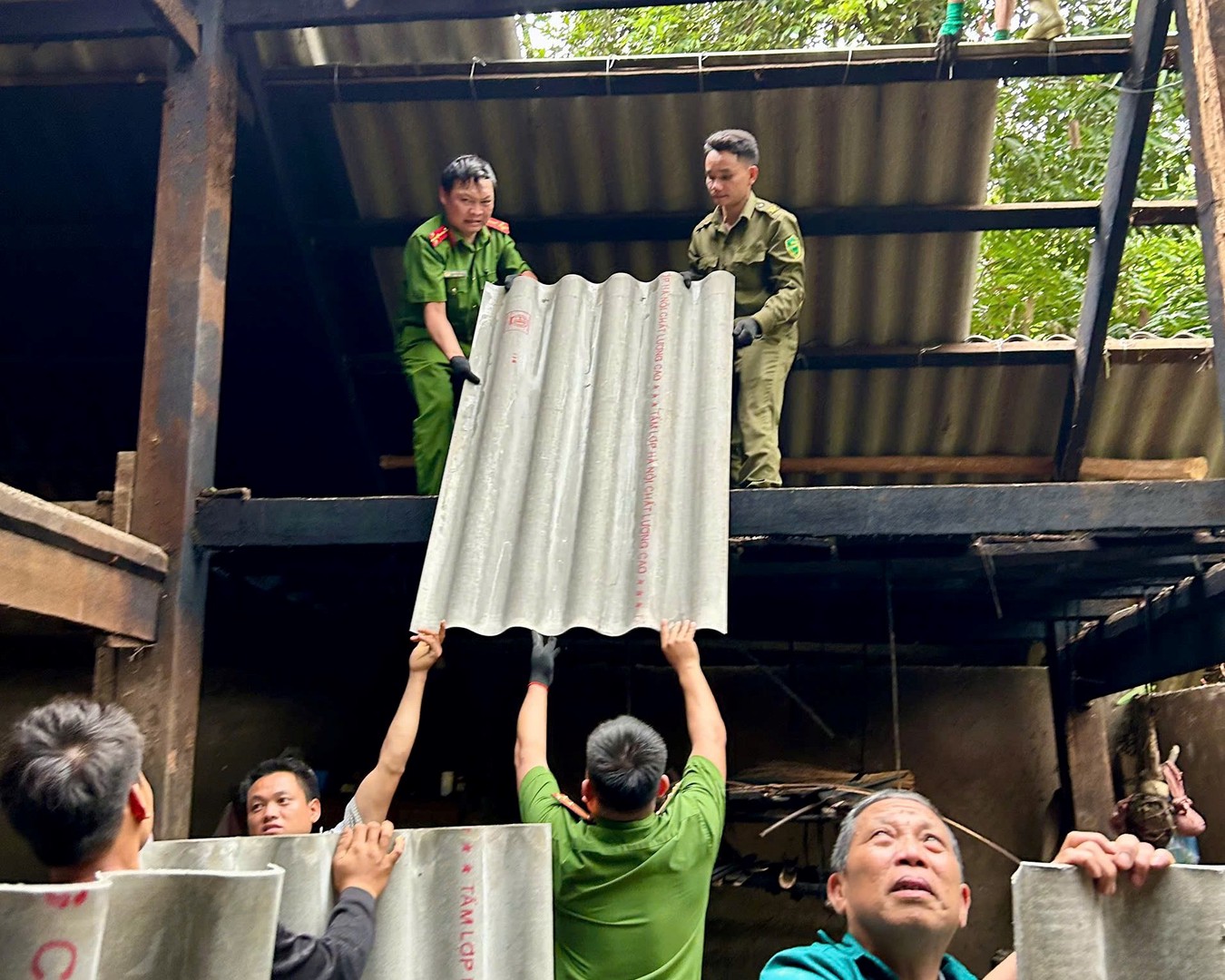 Đoàn viên thanh niên Công an xã và lực lượng an ninh cơ sở hỗ trợ gia đình lợp lại mái nhà để sớm ổn định cuộc sống.jpg