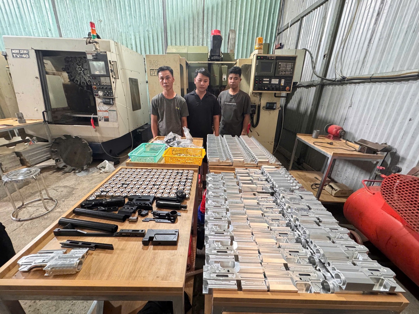 Từ trái qua phải các đối tượng Nguyễn Công Danh, Nguyễn Công Quý (chủ xưởng cơ khí), Trương Anh Tài và số lượng súng cầm tay tại xưởng cơ khí.jpg
