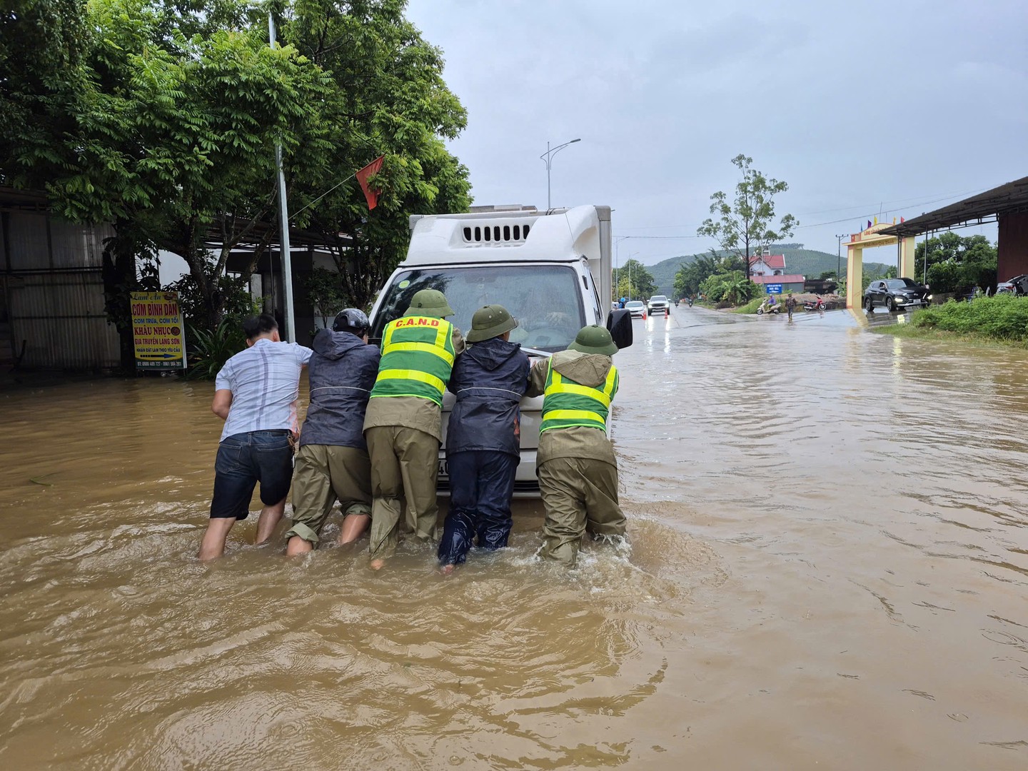 Công an xã Trường Sơn hỗ trợ người dân di chuyển xe bị chết máy ở đoạn nước ngập sâu.jpg